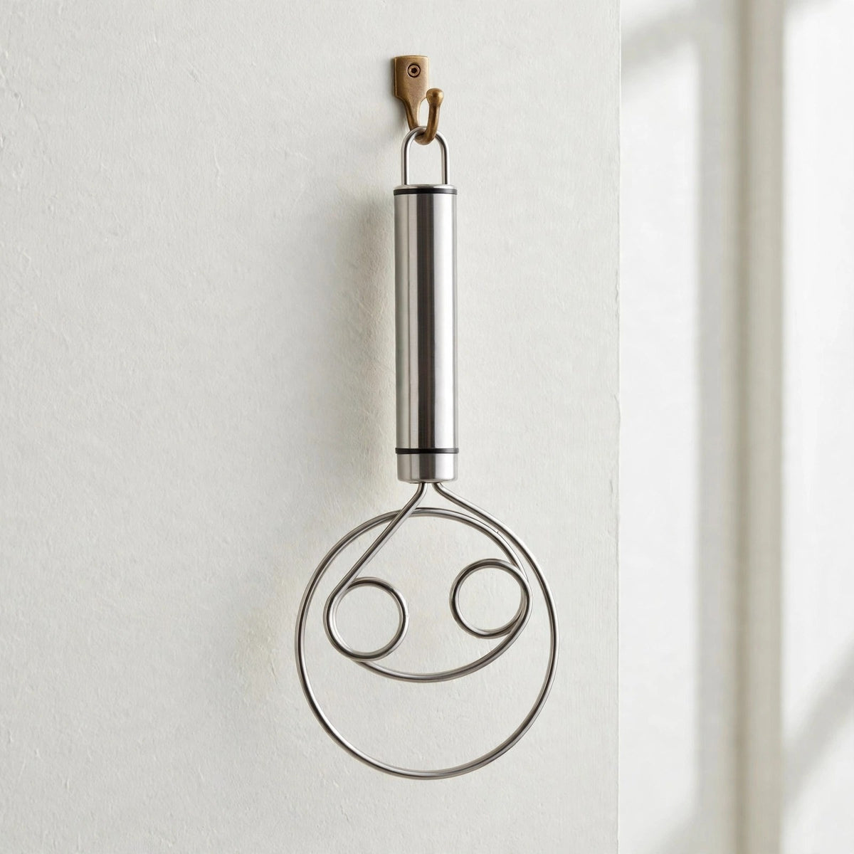 Fouet Cristal suspendu par son anneau à un crochet mural, manche tube en inox