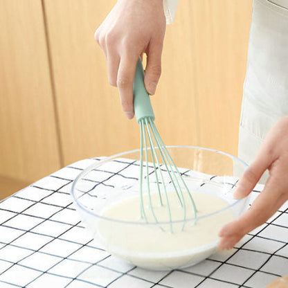 Fouet FlexiPro vert fouettant une pâte blanche dans un bol en verre, prise en main