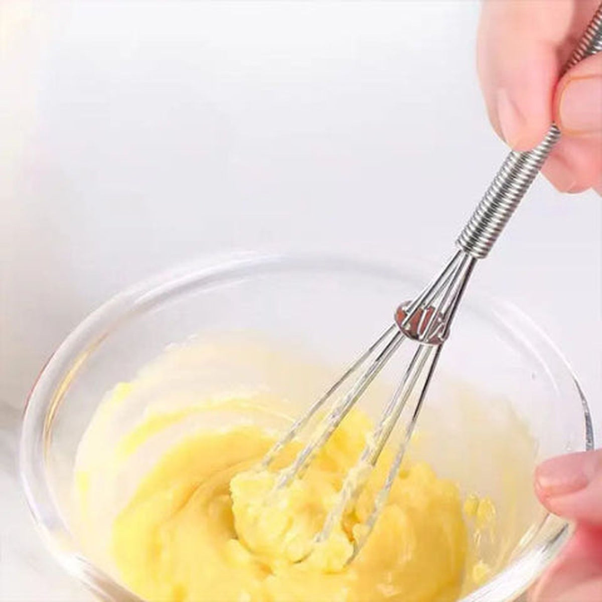 Fouet Fusion en inox battant une crème épaisse dans un bol en verre