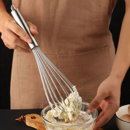 Grand fouet InoxStar en inox soulevant une pâte épaisse dans un bol en verre