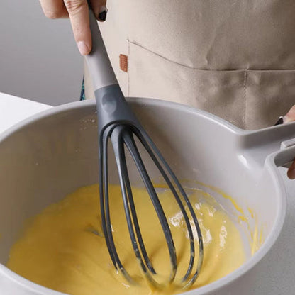 Fouet plat Aromova gris aux fils gainés mélangeant une pâte dans une casserole blanche