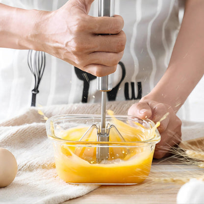 Tête du fouet PushMix en inox en rotation dans un plat d'œufs battus, main appuyant sur le manche