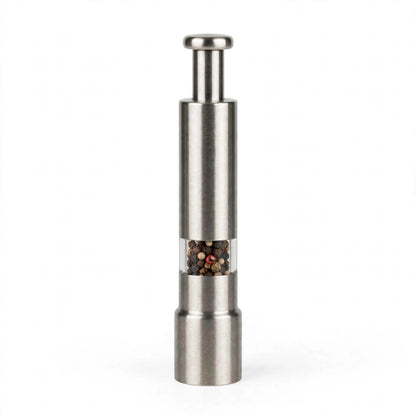 Moulin à poivre à piston en acier inoxydable sur fond blanc : bouton-poussoir rond, fenêtre transparente remplie de grains de poivre mélangés, base en inox brossé