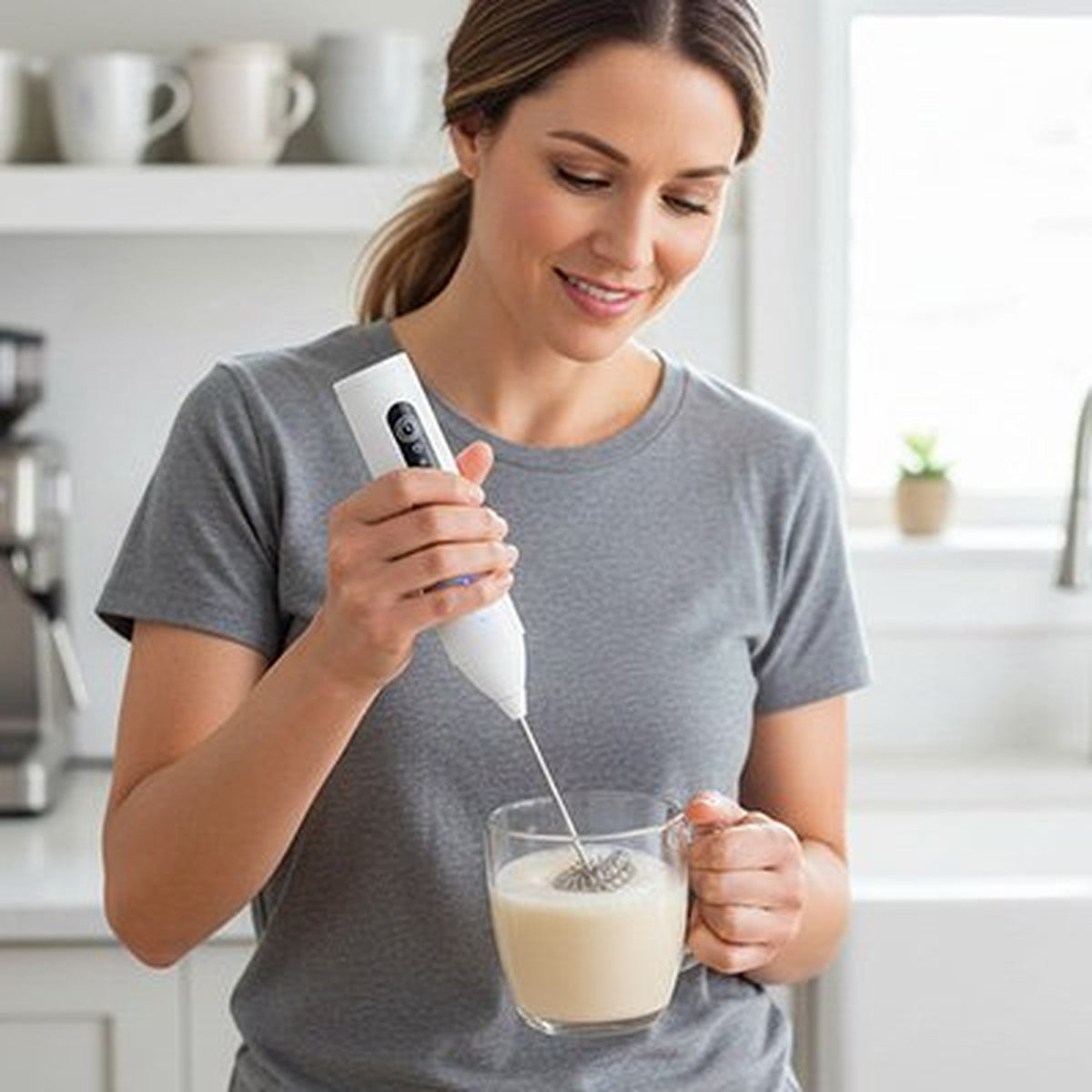 Femme utilisant le mousseur à lait KREAMIX EXPRESS blanc dans une tasse de lait
